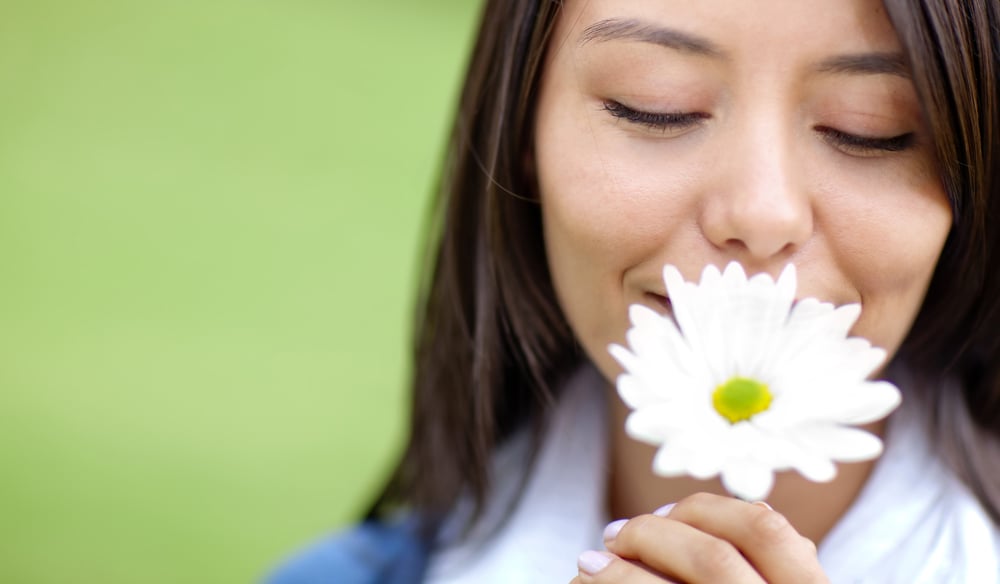 Beautiful woman portrait smelling a flower outdoors